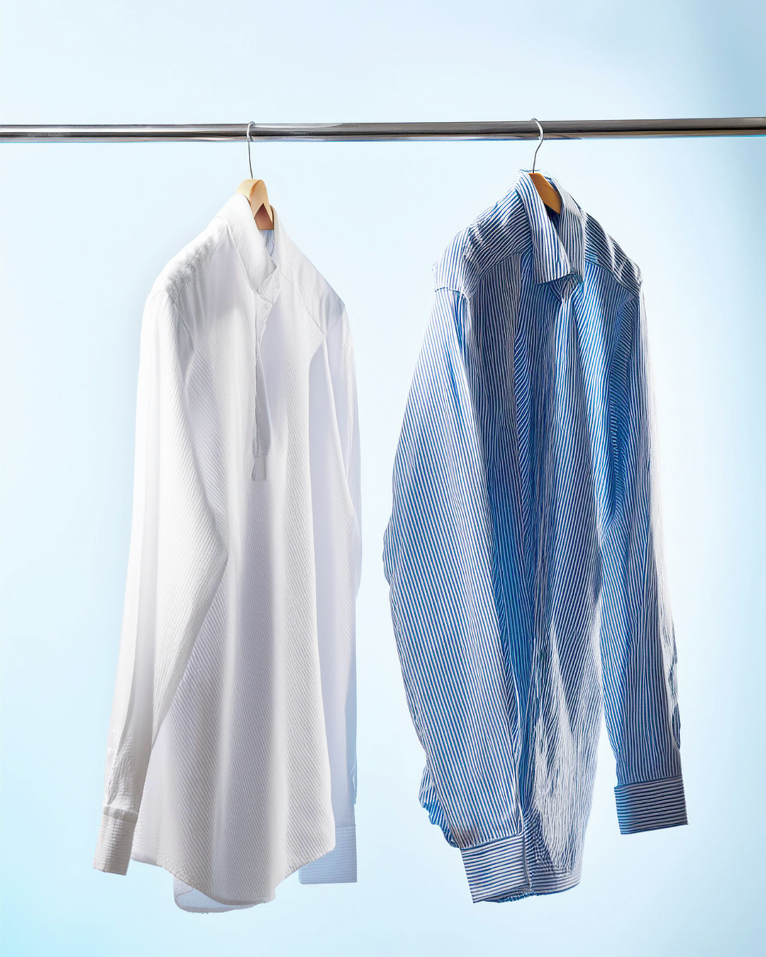 White and blue striped dress shirts hanging on a clothing rack